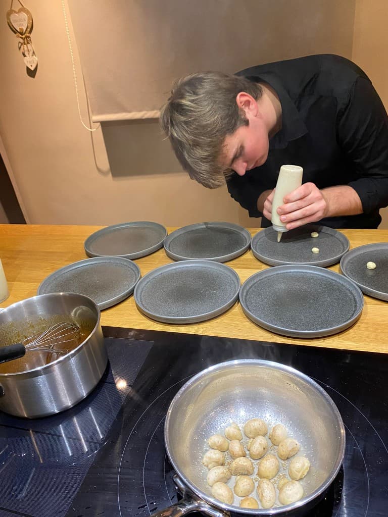 Chef die met precisie borden dresseert voor service — close-up van het finishen
