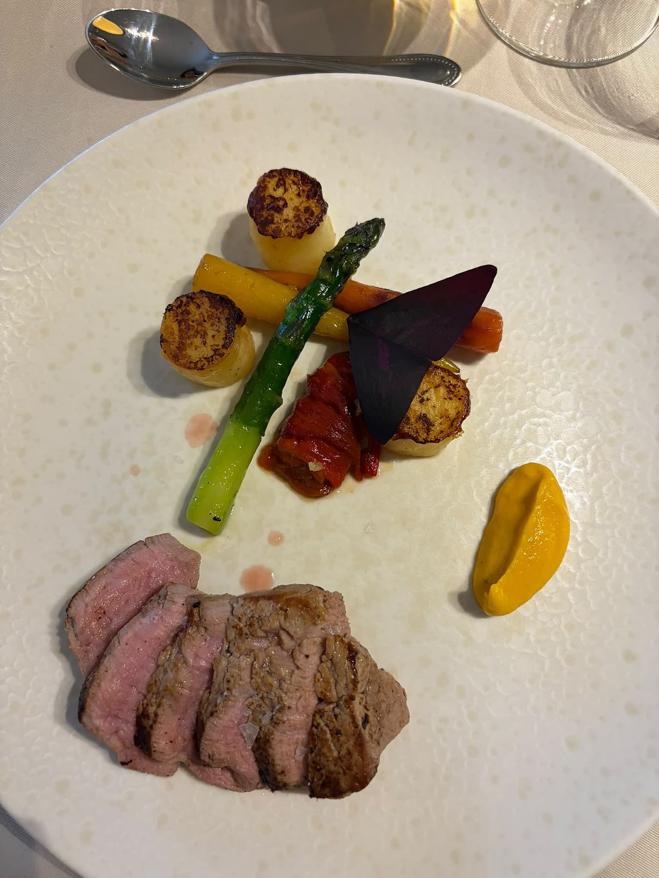 Rund met asperge, groenten en crème op wit bord